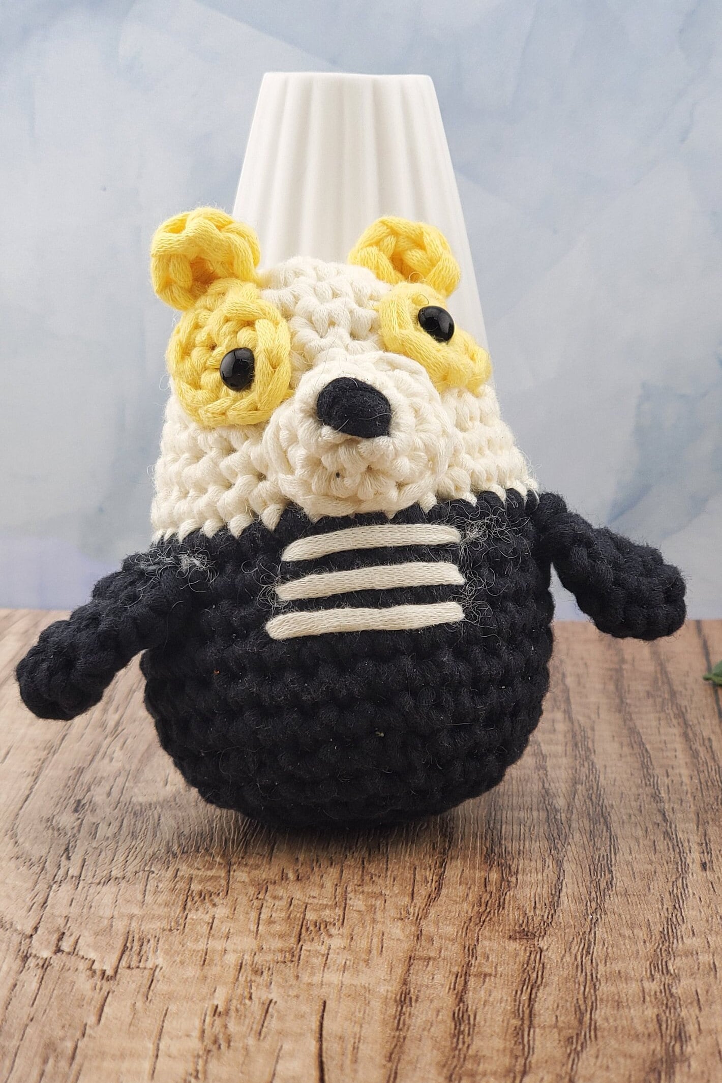 Handcrafted crocheted badger buddy named Hudson. White and black with yellow ears.