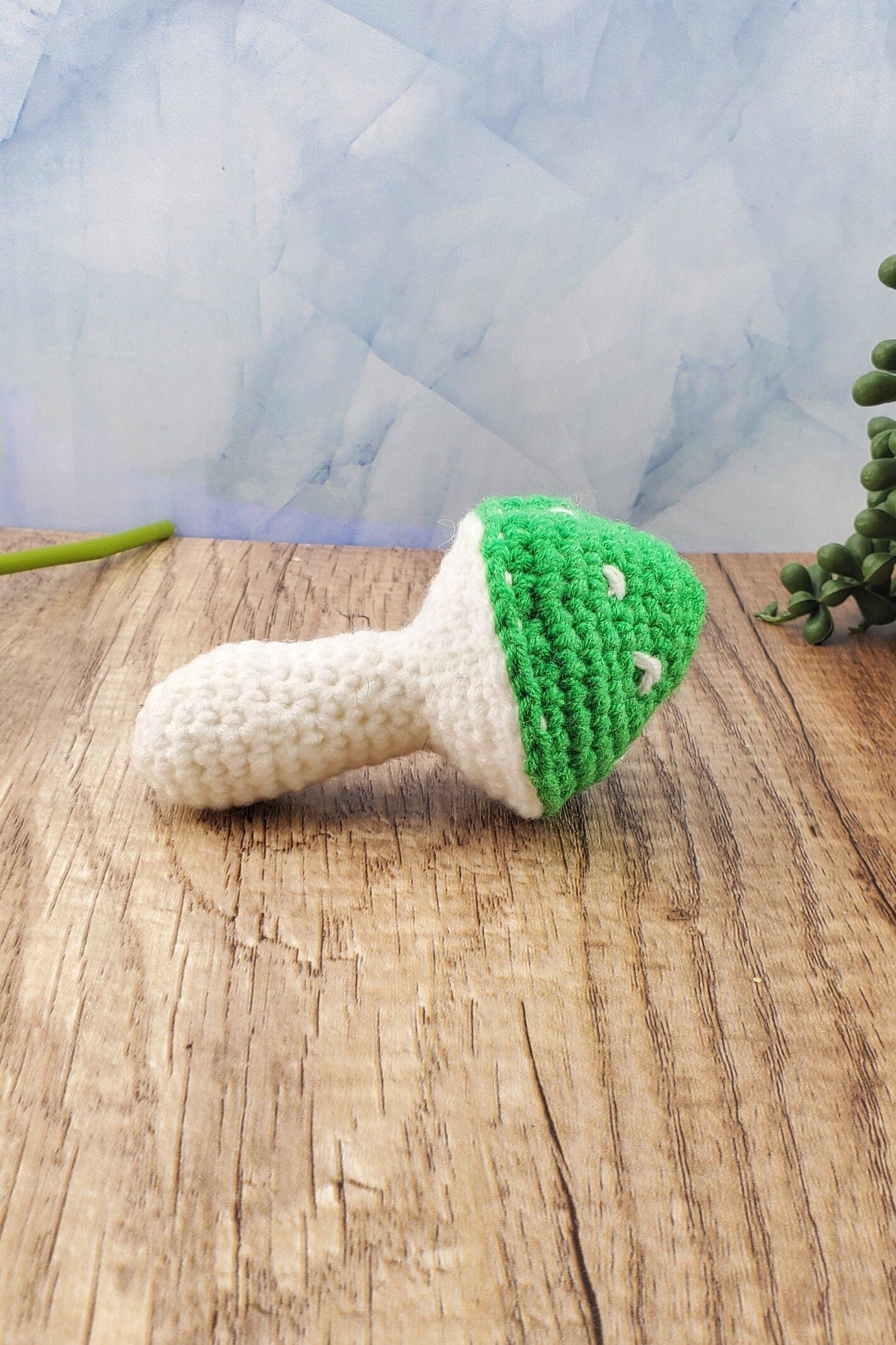 Handcrafted crocheted mushroom buddy named Miles. White and green mushroom with white spots.