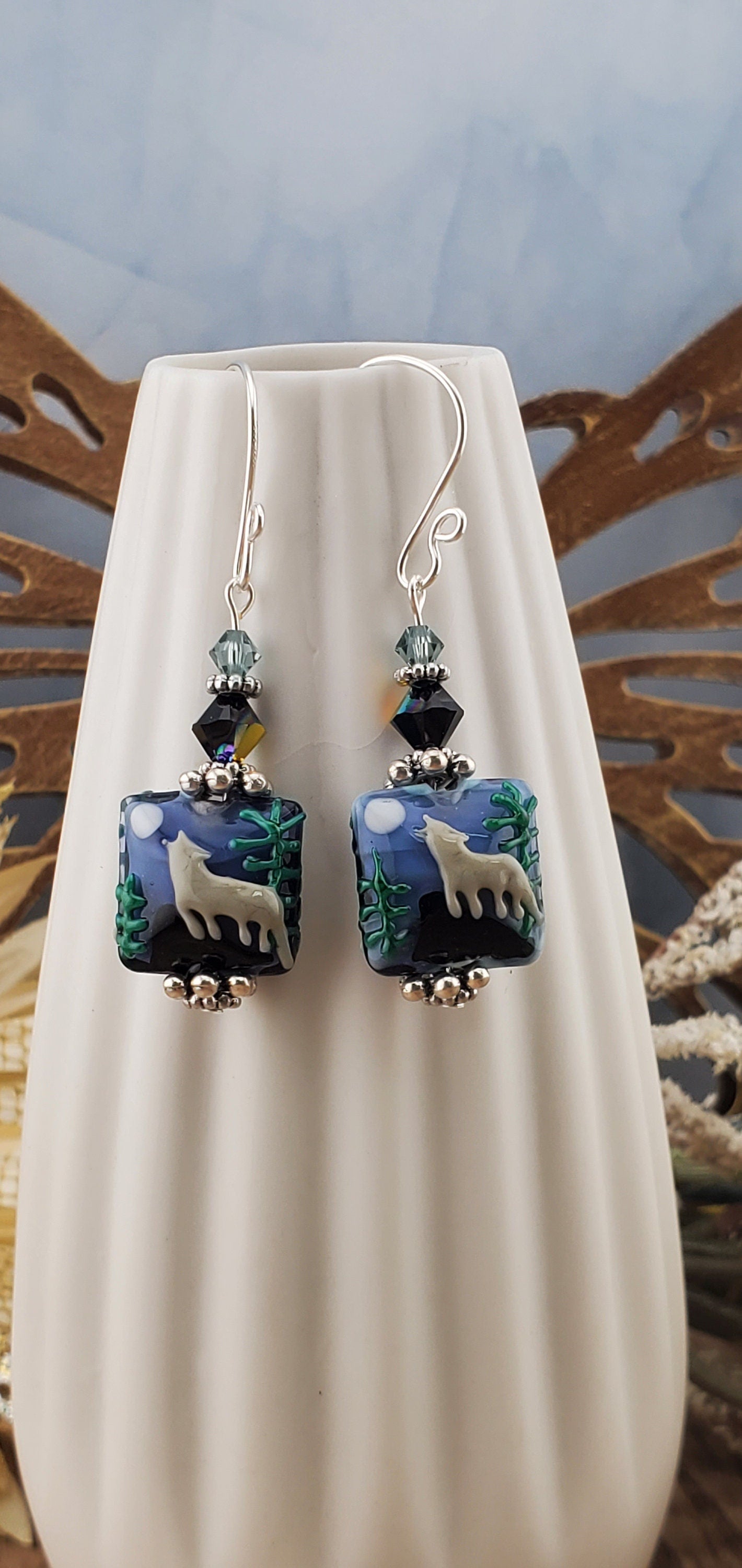 SF Twilight Serenade Artisan Glass Earrings, Lampwork Glass Bead handcrafted by a talented artisan, Silver Filled Earring Wire. Howling wolf under a full moon in the forest lampwork bead. Accented with blue crystals.