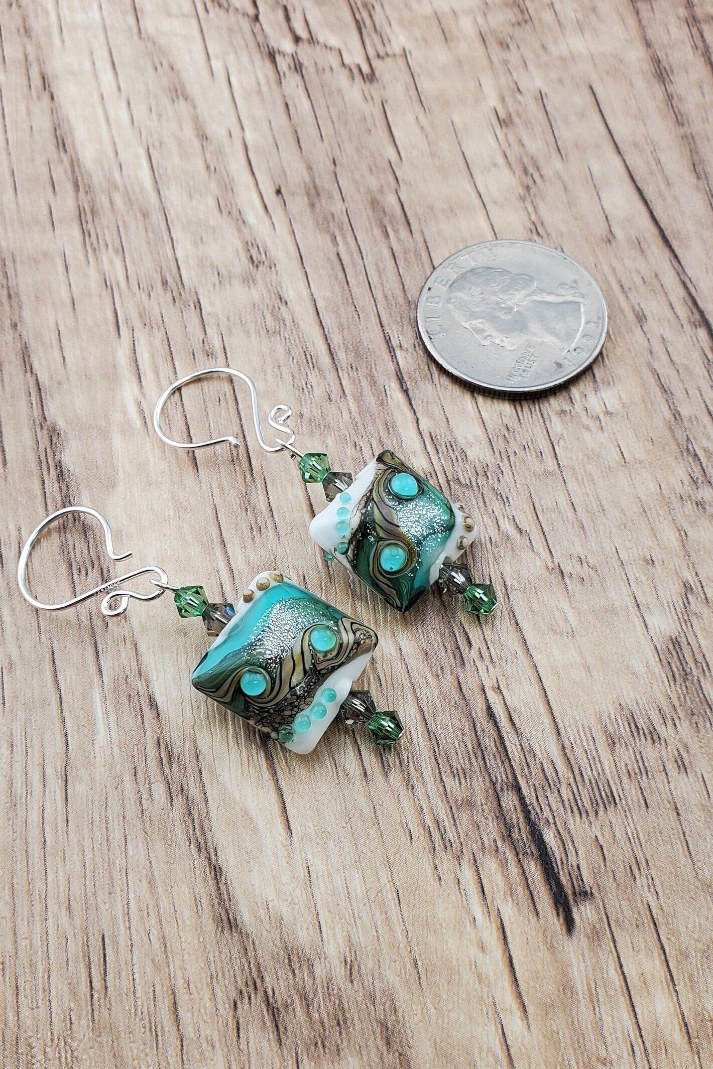 SF Coastal Breeze Artisan Glass Earrings, Lampwork Glass Bead handcrafted by a talented artisan, Silver Filled Earring Wire. Shades of blue, green and browns compliment this lampwork bead. Green and brown crystals adorn the bead.