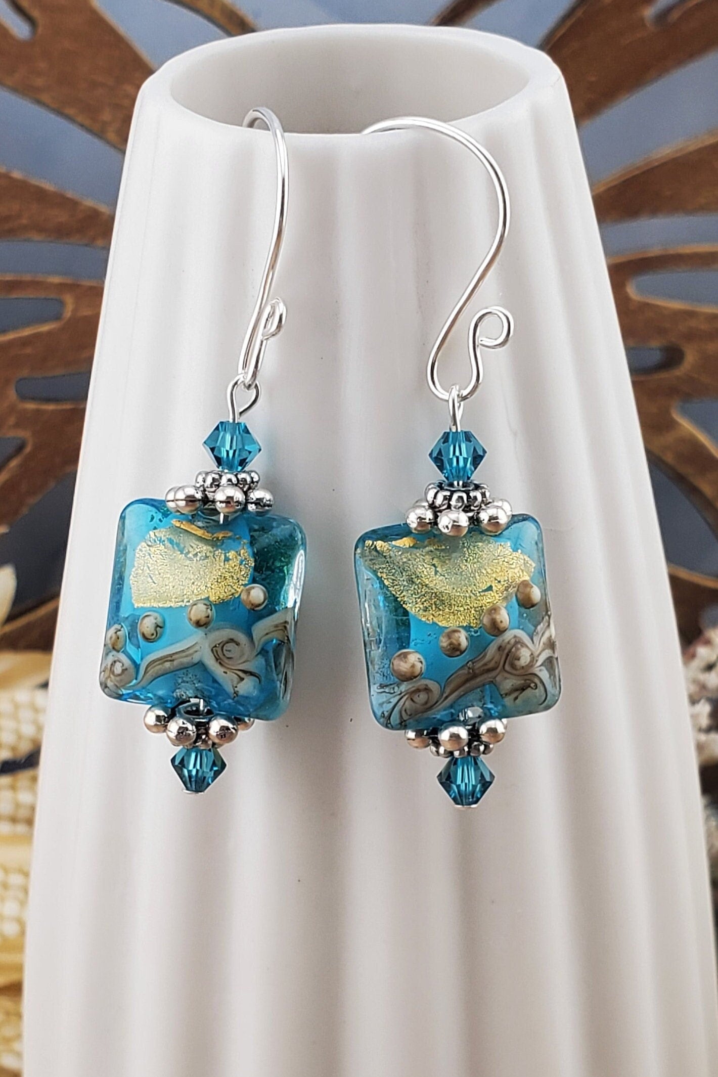 SF Golden Horizon Blues Artisan Glass Earrings, Lampwork Glass Bead handcrafted by a talented artisan, Silver Filled Earring Wire. Teal and golden colors fill this lampwork bead and it is accented with teal crystals.