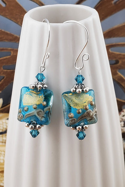 SF Golden Horizon Blues Artisan Glass Earrings, Lampwork Glass Bead handcrafted by a talented artisan, Silver Filled Earring Wire. Teal and golden colors fill this lampwork bead and it is accented with teal crystals.