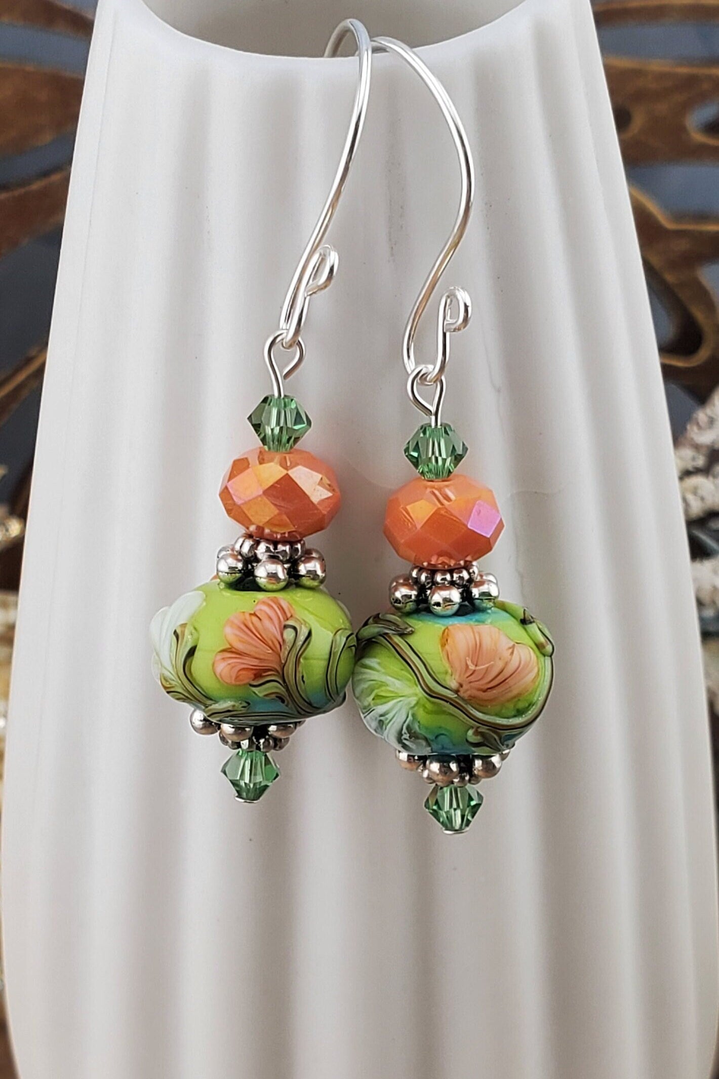 SF Citrus Blossom Glow Artisan Glass Earrings, Lampwork Glass Bead handcrafted by a talented artisan, Silver Filled Earring Wire. Orange and Green crystal bead along with a green and orange floral lampwork bead.