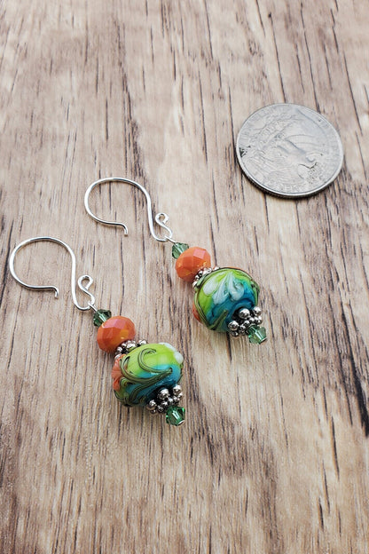 SF Citrus Blossom Glow Artisan Glass Earrings, Lampwork Glass Bead handcrafted by a talented artisan, Silver Filled Earring Wire. Orange and Green crystal bead along with a green and orange floral lampwork bead.