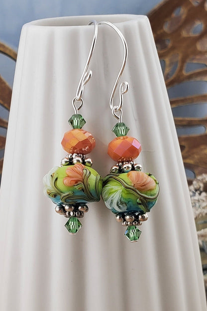 SF Citrus Blossom Glow Artisan Glass Earrings, Lampwork Glass Bead handcrafted by a talented artisan, Silver Filled Earring Wire. Orange and Green crystal bead along with a green and orange floral lampwork bead.