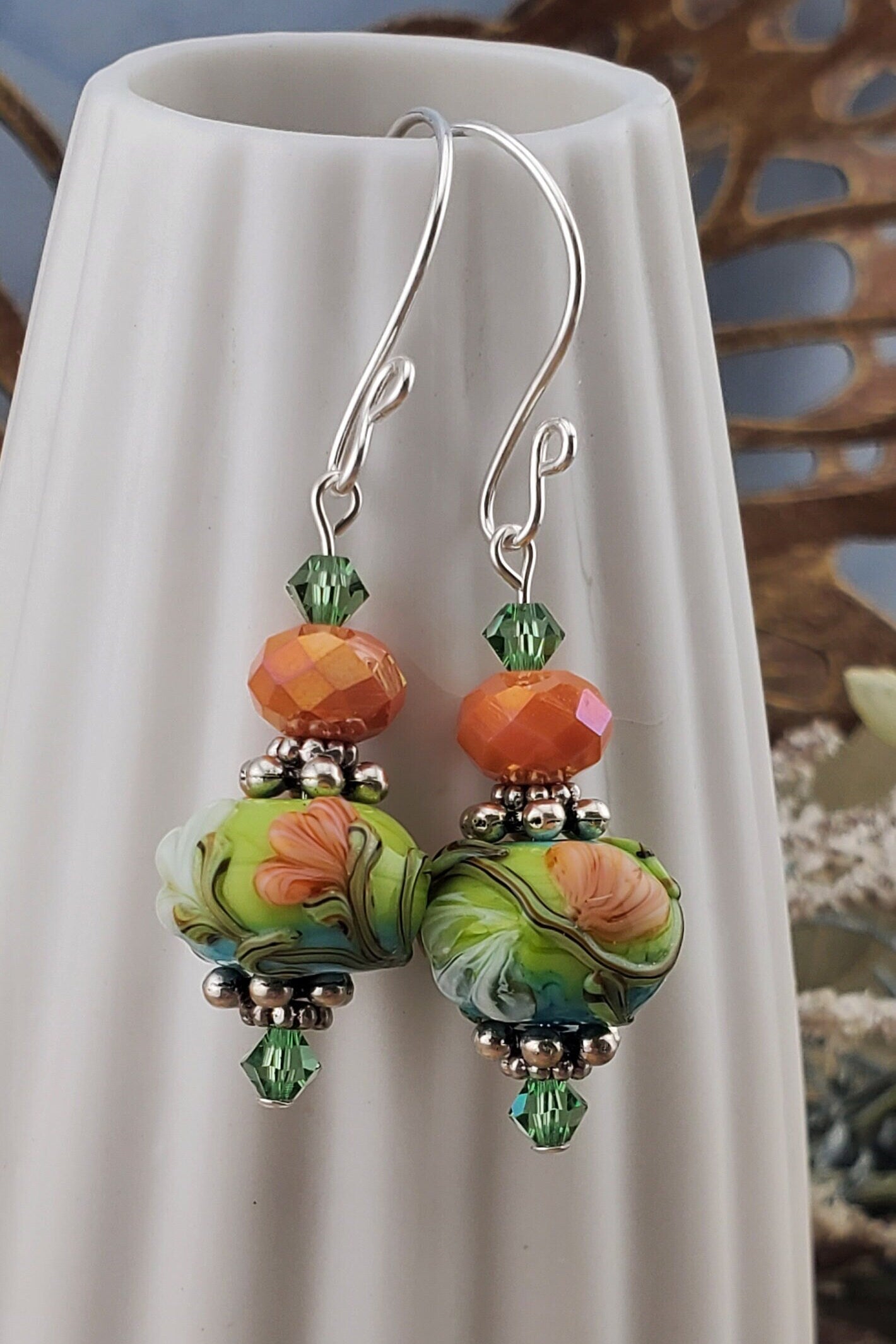 SF Citrus Blossom Glow Artisan Glass Earrings, Lampwork Glass Bead handcrafted by a talented artisan, Silver Filled Earring Wire. Orange and Green crystal bead along with a green and orange floral lampwork bead.