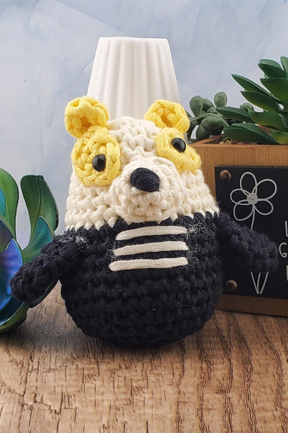 Handcrafted crocheted badger buddy named Hudson. White and black with yellow ears.