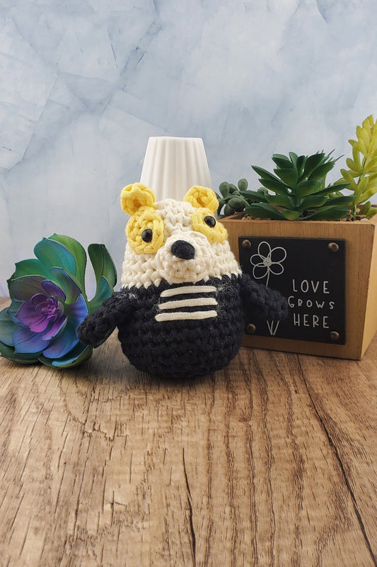 Handcrafted crocheted badger buddy named Hudson. White and black with yellow ears.