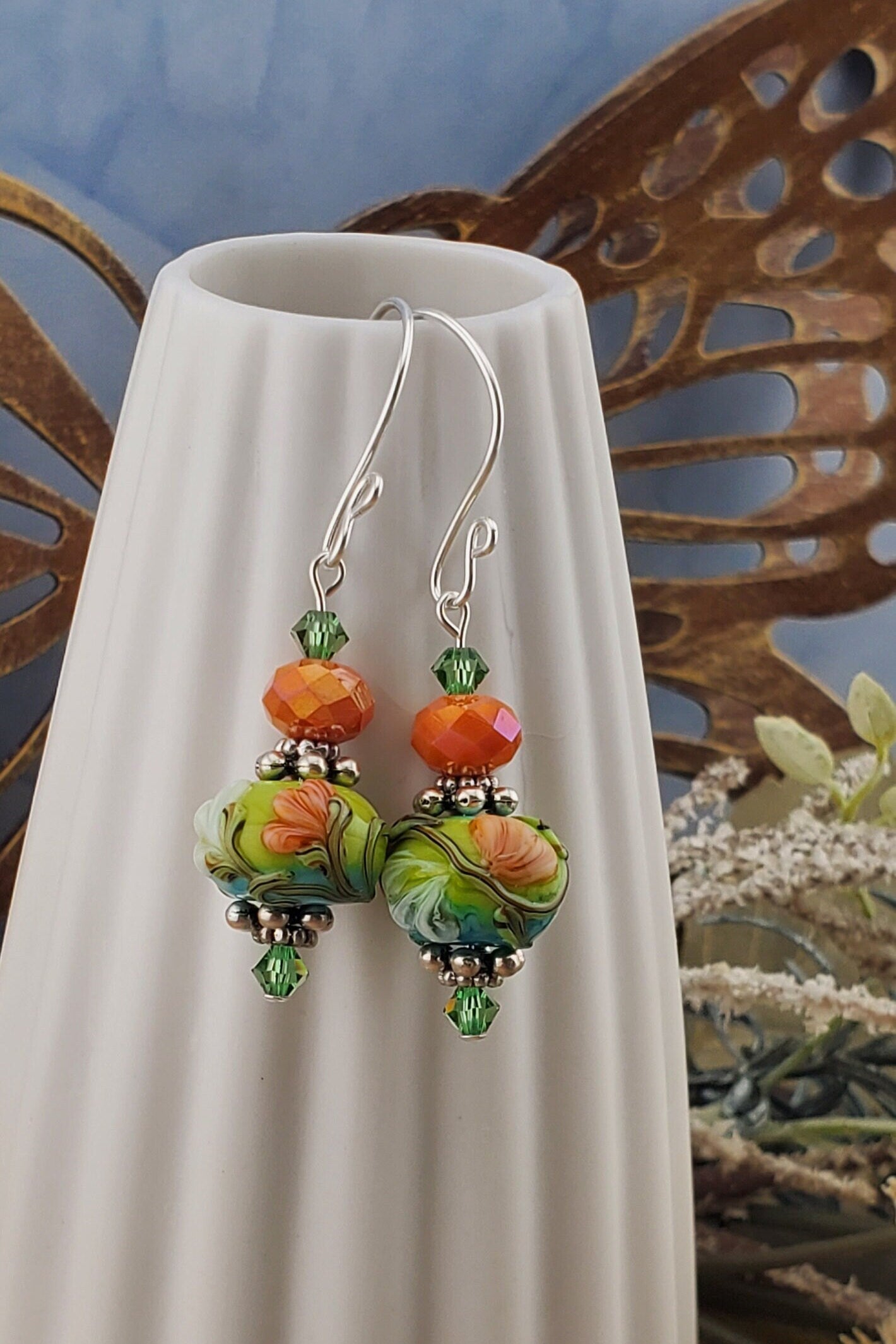 SF Citrus Blossom Glow Artisan Glass Earrings, Lampwork Glass Bead handcrafted by a talented artisan, Silver Filled Earring Wire. Orange and Green crystal bead along with a green and orange floral lampwork bead.