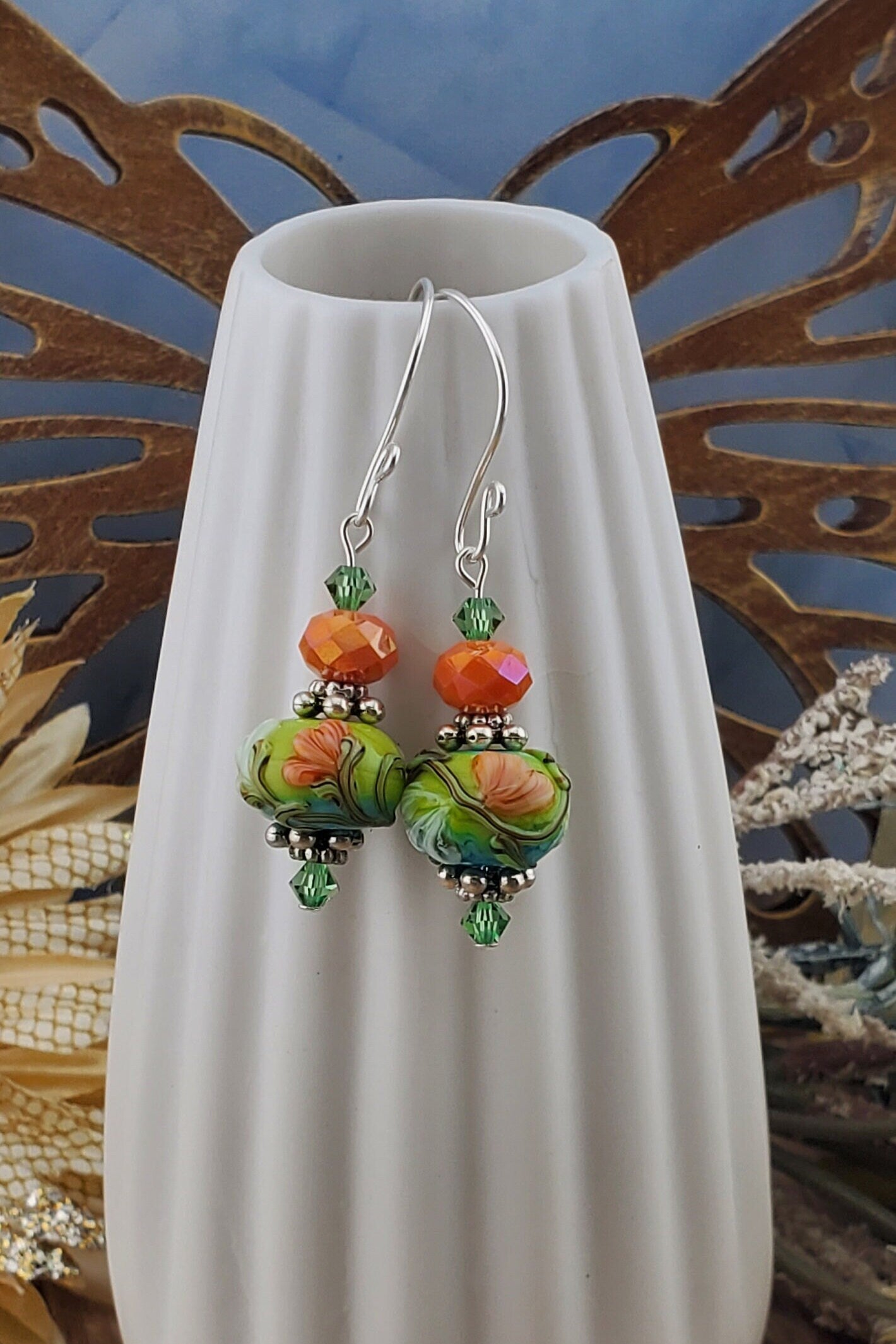 SF Citrus Blossom Glow Artisan Glass Earrings, Lampwork Glass Bead handcrafted by a talented artisan, Silver Filled Earring Wire. Orange and Green crystal bead along with a green and orange floral lampwork bead.