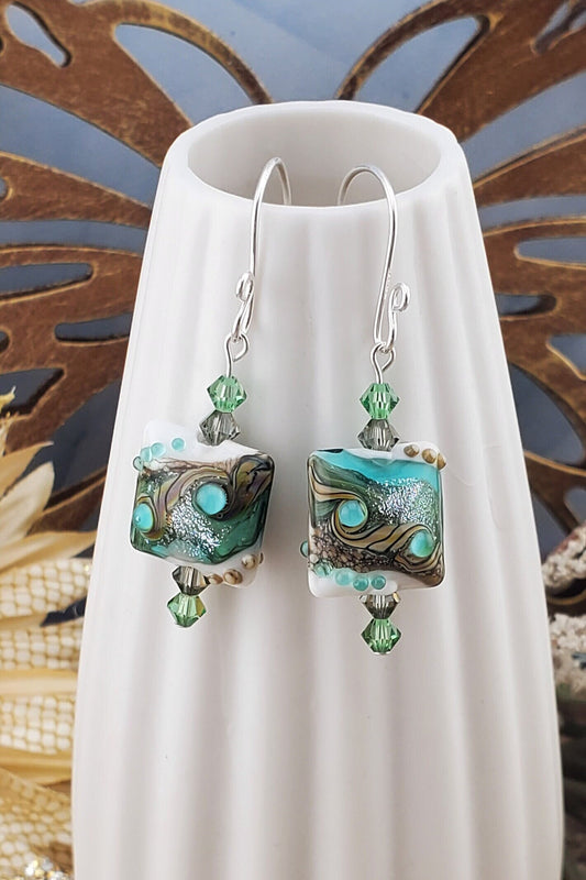 SF Coastal Breeze Artisan Glass Earrings, Lampwork Glass Bead handcrafted by a talented artisan, Silver Filled Earring Wire. Shades of blue, green and browns compliment this lampwork bead. Green and brown crystals adorn the bead.