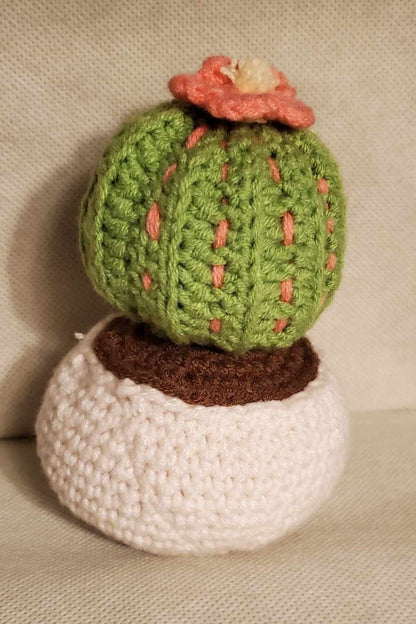 Handcrafted crochet cactus buddy named Sahara chilling in a brown pot, flaunting a sassy pink flower