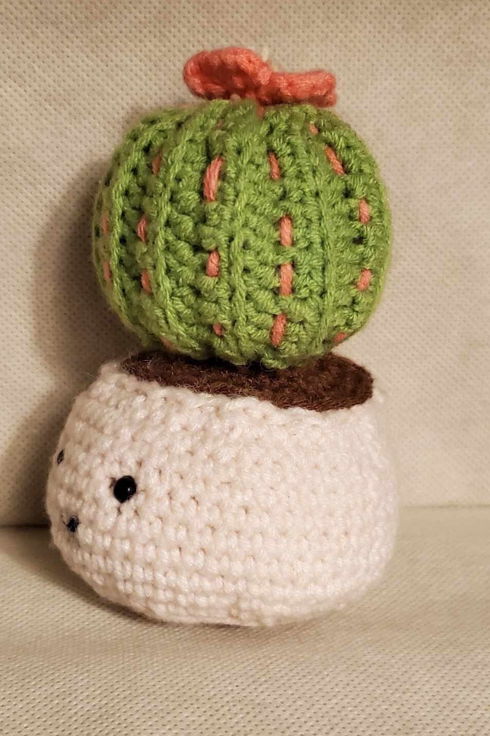 Handcrafted crochet cactus buddy named Sahara chilling in a brown pot, flaunting a sassy pink flower