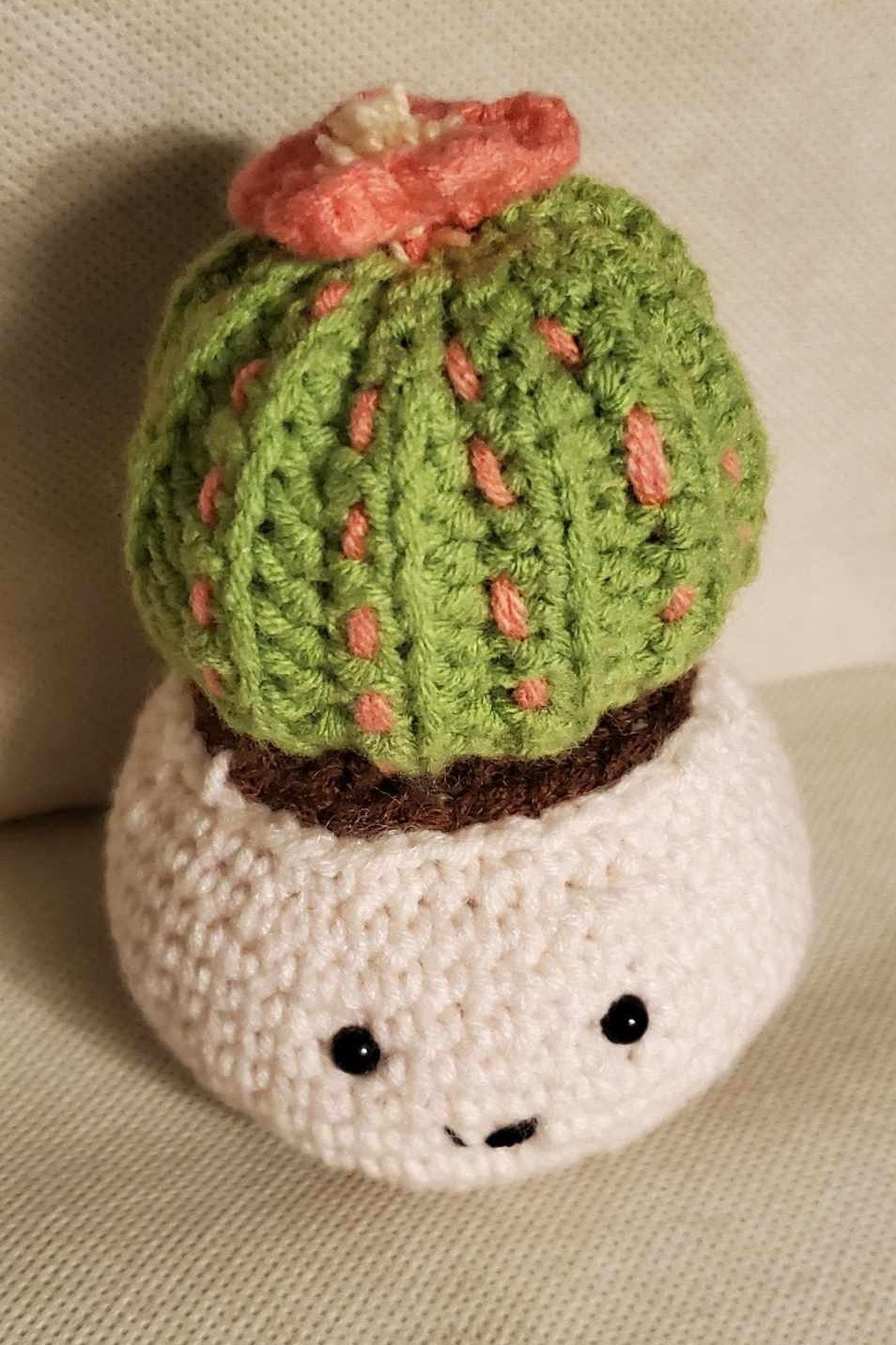 Handcrafted crochet cactus buddy named Sahara chilling in a brown pot, flaunting a sassy pink flower